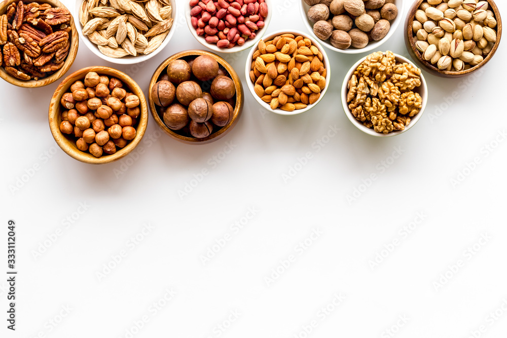 Fototapeta premium Set of macadamia, hazelnut, walnut, almond, pistachio, pecans nuts on white background top-down frame copy space