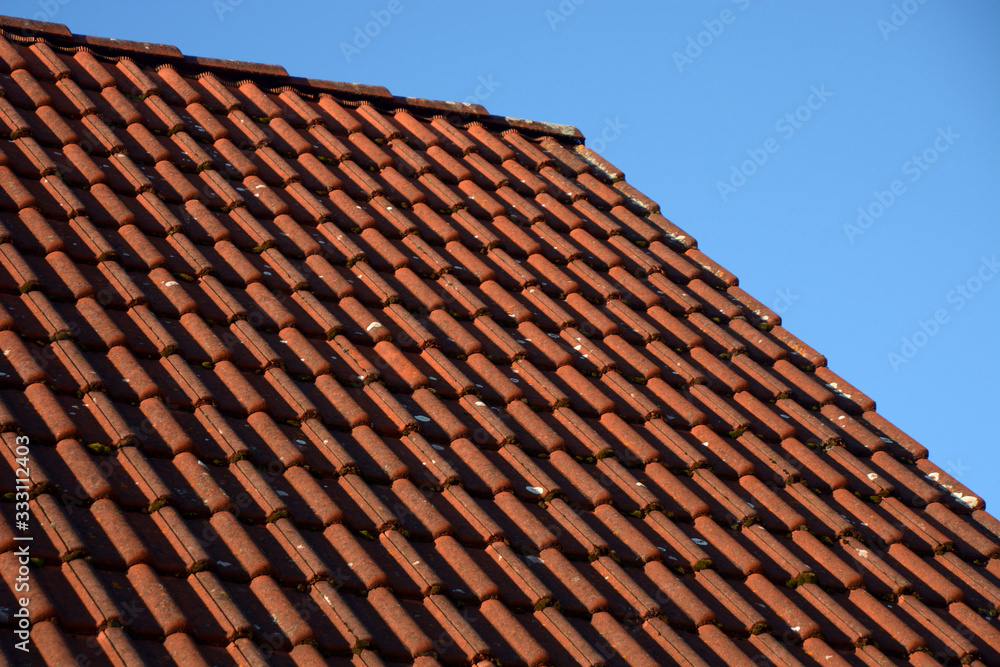dirty roof top lit by sun, red old dirty roof tiles in front of blue sky
