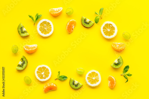 Fototapeta Naklejka Na Ścianę i Meble -  Slices fruites frame. Fruit salad concept with citruses, aplle and kiwi on yellow background top-down copy space