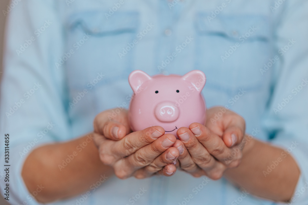 female hands protect pink piggy bank, copy space. Concept of saving money or savings female hands protect pink piggy bank, copy space. Concept of saving money or savings