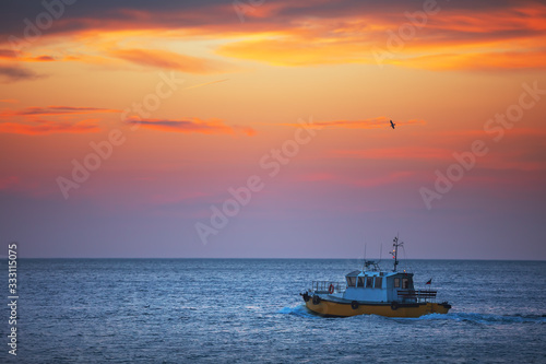 Patrol boat sailing at sunrise in sea water