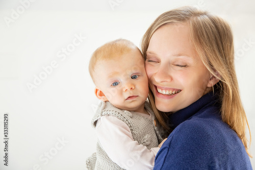 Beautiful happy mother and child. Portrait of happy young mother holding adorable infant baby girl isolated on white background. Parenthood concept