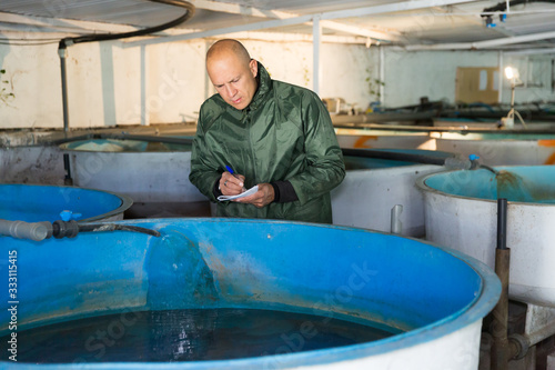 Owner of trout farm checking reservoirs with fry photo