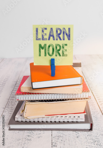 Text sign showing Learn More. Business photo text knowledge or skill acquired by instruction Considerable learning pile stacked books notebook pin clothespin colored reminder white wooden photo