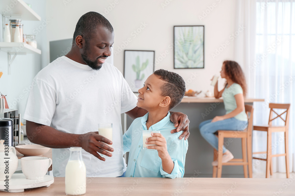 Fototapeta premium African-American boy and his father drinking milk in kitchen