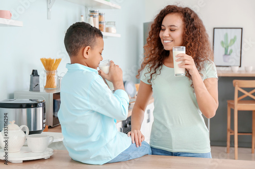 African-American woman and her son drinking milk in kitchen