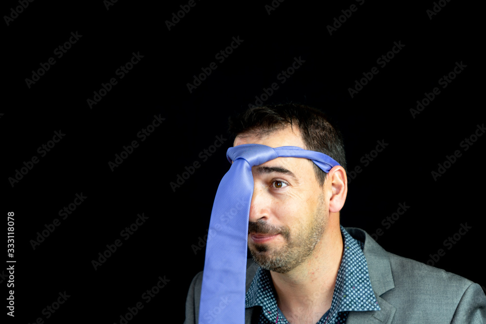 Obraz premium Bearded young man dressed in gray suit posing with tie on head after party night