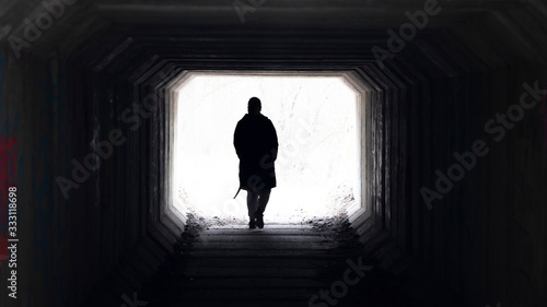 Silhouette of man light at the end of the tunnel.