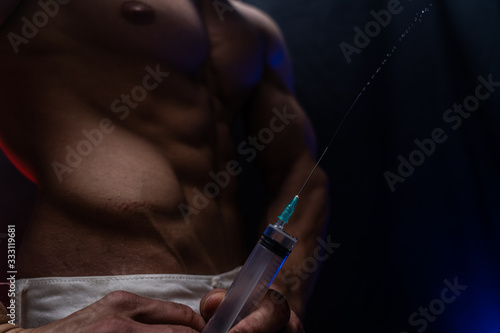 Bodybuilder holding big syringe with injection. concept of steroid in the sport and addiction 