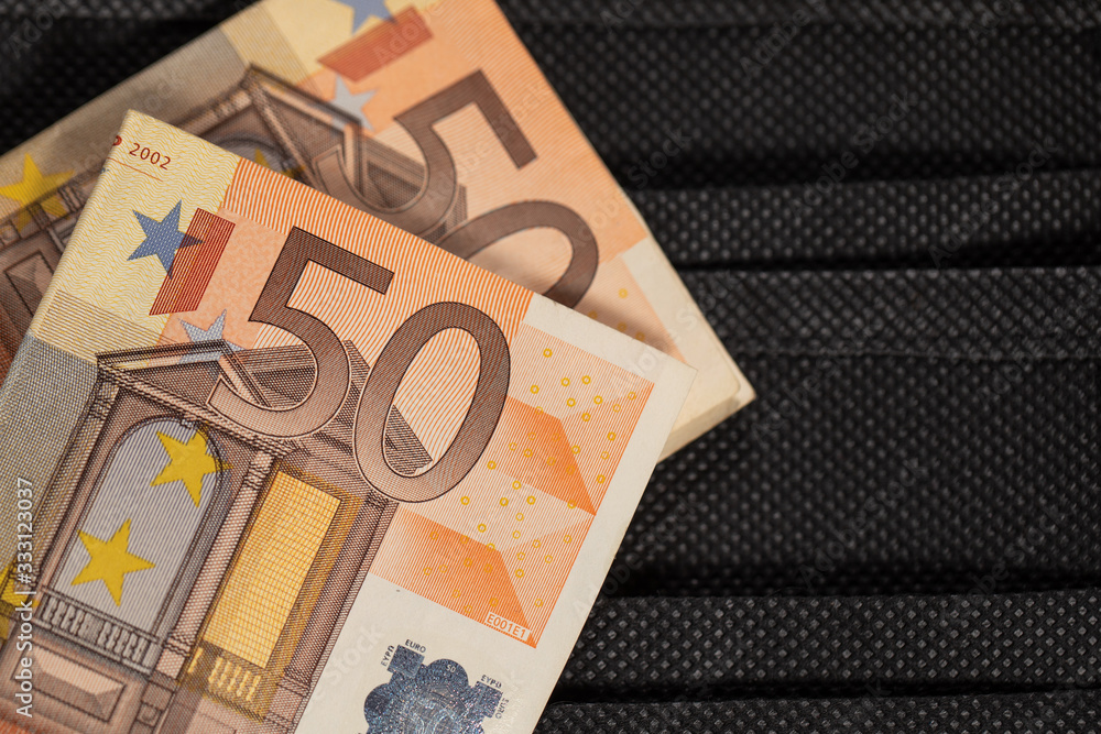 50 Euro on the background of medical mask. black medical masks and cash money. illustration of expensive mask prices. crisis 2020, coronavirus concept. Covid-19. 50 Euro on the background of medical mask. black medical masks and cash money. illustration of expensive mask prices. crisis 2020, coronavirus concept. Covid-19.