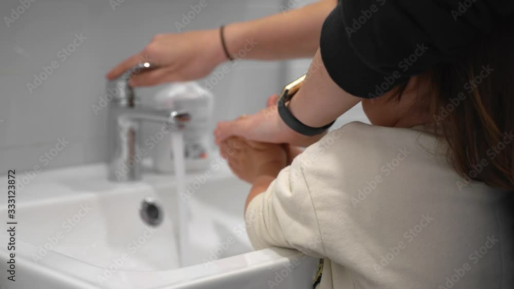Young mother with child washing hands at home with antibacterial soap Young mother with child washing hands at home with antibacterial soap