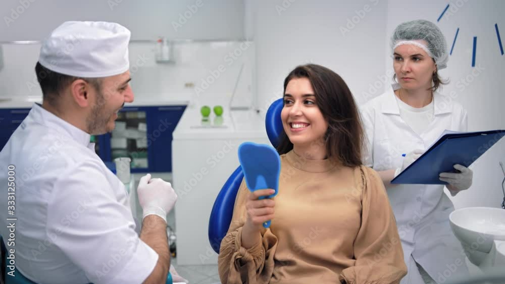 Satisfied woman client of dentistry look at mirror after tooth whitening. 4k Dragon RED camera Satisfied woman client of dentistry look at mirror after tooth whitening. 4k Dragon RED camera
