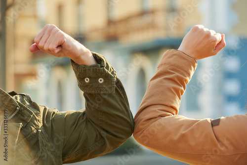 Elbow greeting to avoid the spread of coronavirus (COVID-19). Colleagues meet on the street with bare hands. Instead of greeting with a hug or handshake, they bump elbows instead. photo