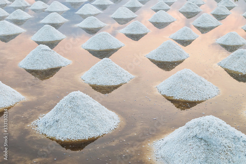 Foto Sea salt pile pyramid ready for harvest in salt farm at sunrise