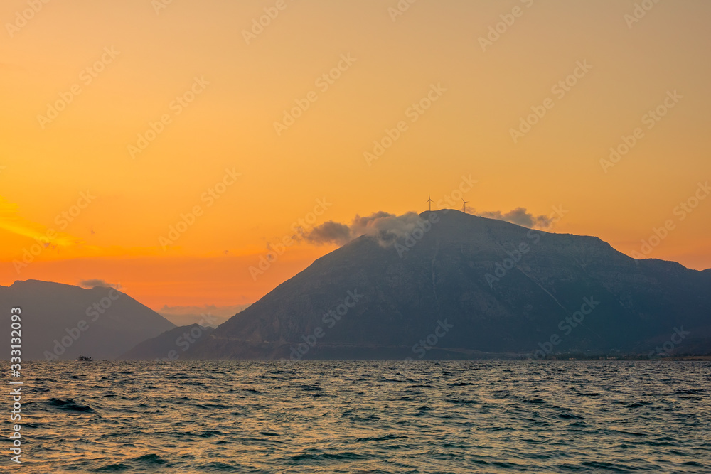 Wind Farms and a Cloud on Top of a Mountainous Shore at Sunset