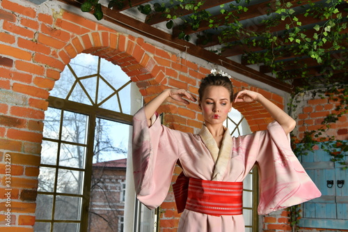 girl in japanese kimono posing on the background of flowering plants