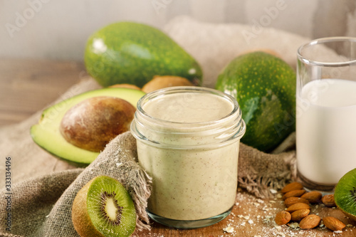 A fresh smoothie of kiwi, avocado, oatmeal and skim milk near a burlap towel. Close up. Morning meal in the village with fresh ingredients.