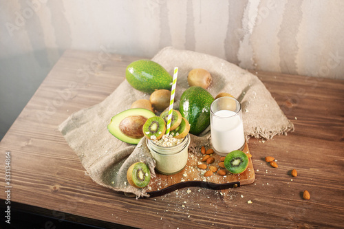 Fresh smoothie made of kiwi, avocado, oatmeal and skim milk near a burlap towel. Decorated on top. Morning meal in the village with fresh ingredients.