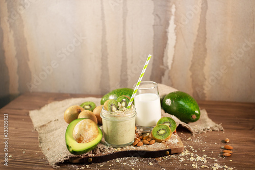 Fresh smoothie made of kiwi, avocado, oatmeal and skim milk near a burlap towel. Decorated on top. Morning meal in the village with fresh ingredients.