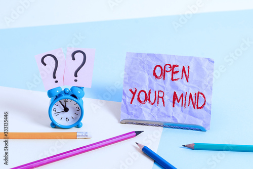 Text sign showing Open Your Mind. Business photo showcasing to be able to understand different ideas or ways of thinking Mini size alarm clock beside stationary placed tilted on pastel backdrop