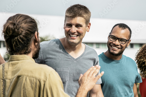 Happy multiracial people talking outdoors. Young multiethnic men and women standing together and talking on street. Communication concept