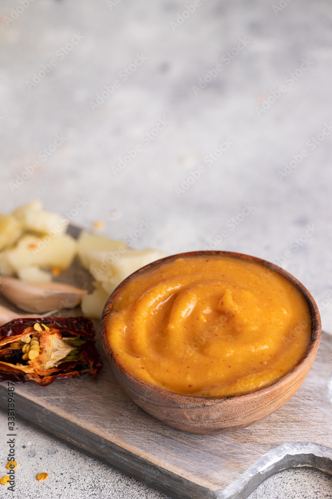 Fototapeta premium Almogrote , cheese paste form La Gomera, Canary Islands in wooden bowl on cut board with hard goat cheese, peppers and garlic.Close up.Copy space