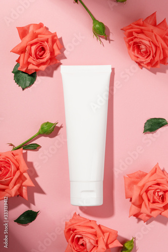 White unbranded flacon isolated on pink background. Body lotion or soft face cream. Mockup style. Flower for decorations, eco-friendly cosmetics. Wellness and luxury organic cosmetology concept photo