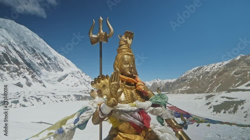 Golden statue of Lord Shiva shine at snowy Himalayas highlands against blue sky