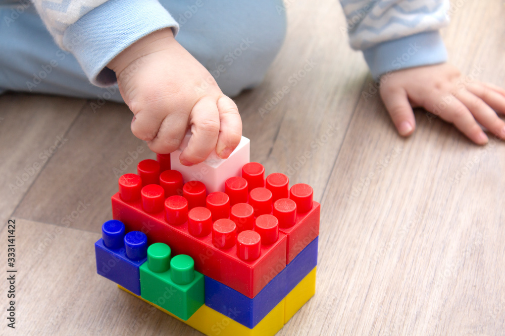 Close-up of children's hands playing with colored plastic bricks. The kid has fun and builds from bright construction bricks. Early learning. Educational toys