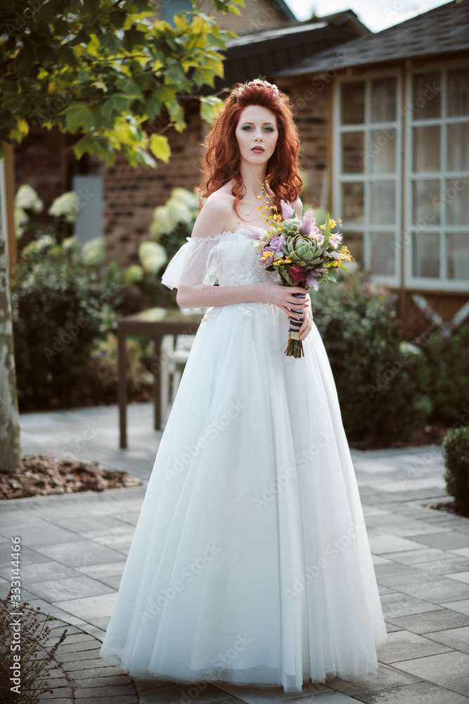 Young bride wearing wedding dress and posing outside