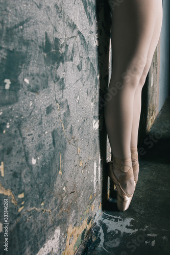 Legs of young ballerina with pointe shoes by the grunge wall