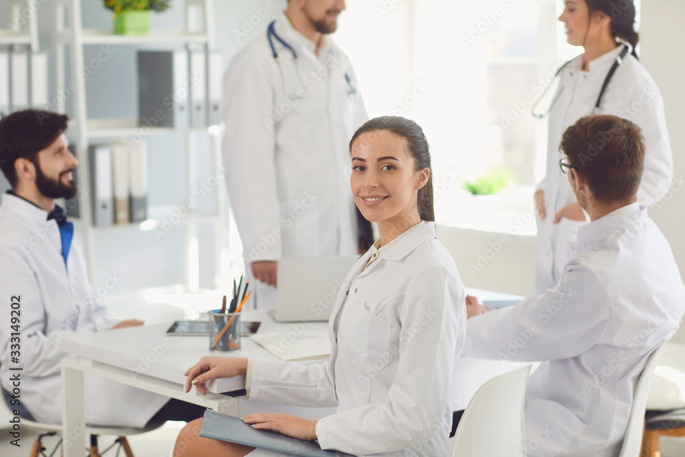 Female doctor sitting at a table with collegues in white lab coats at a medical hospital. Female doctor sitting at a table with collegues in white lab coats at a medical hospital.