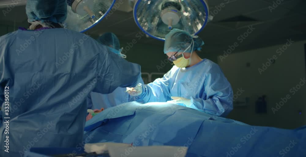 Pan Medical Assistant Passing Scissors to Surgeon