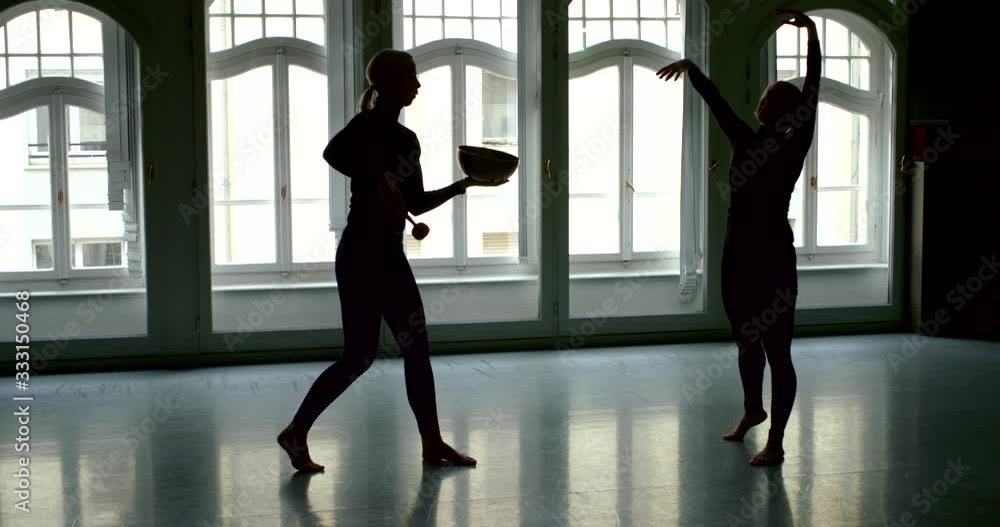 session of sound therapy, woman is dancing by music from standing bell in hands of female therapist session of sound therapy, woman is dancing by music from standing bell in hands of female therapist