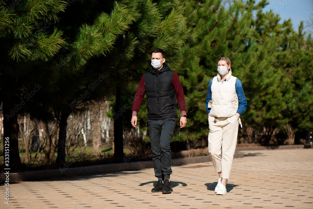 Young European man and woman in protective disposable medical mask walking outdoors afraid of dangerous NCoV 2019 influenza coronavirus mutated and spreading in China Young European man and woman in protective disposable medical mask walking outdoors afraid of dangerous NCoV 2019 influenza coronavirus mutated and spreading in China