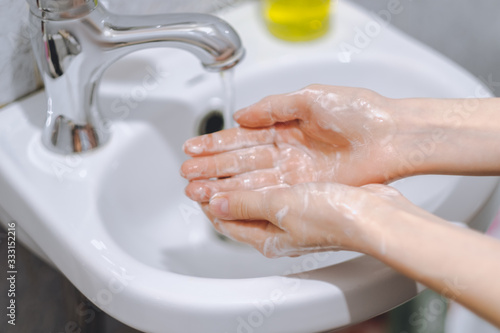 Woman washes hands with liquid soap at home in the bathroom