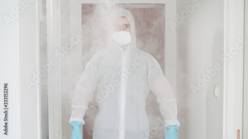 Person in pandemic clothing decontaminate with spray