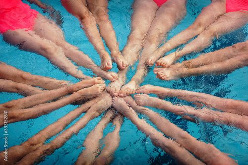 The legs of the synchronized swimmers girls peek out from the pool water and create the shape of a star in a show performance
