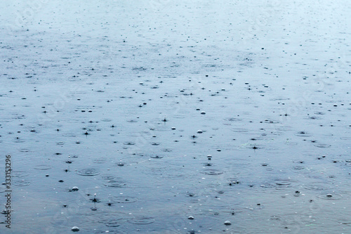 drop of rainwater falls into dark surface water during the rainy season