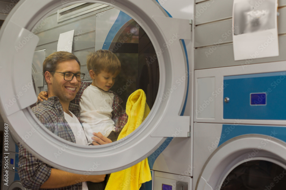 father teaching son how to use washing machine at the laundry shop father teaching son how to use washing machine at the laundry shop