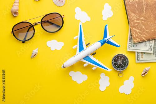 Travel accessories and items on a yellow background Toy airplane in the clouds and a passport, money, glasses