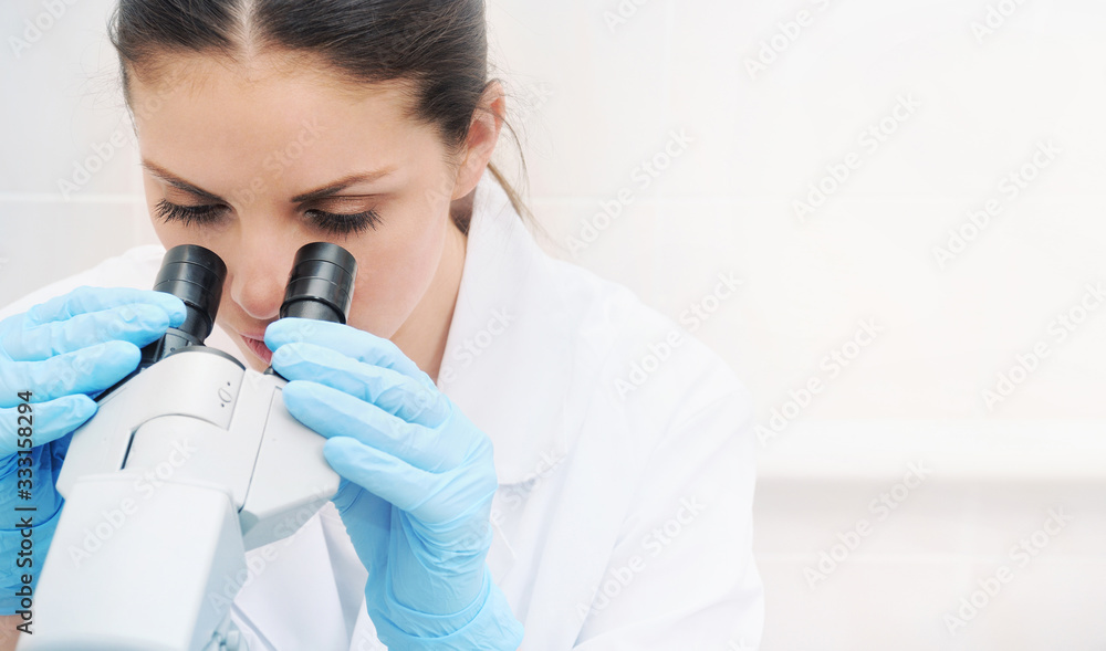 Close up portrait of young medical researcher looking through microscope in laboratory Close up portrait of young medical researcher looking through microscope in laboratory