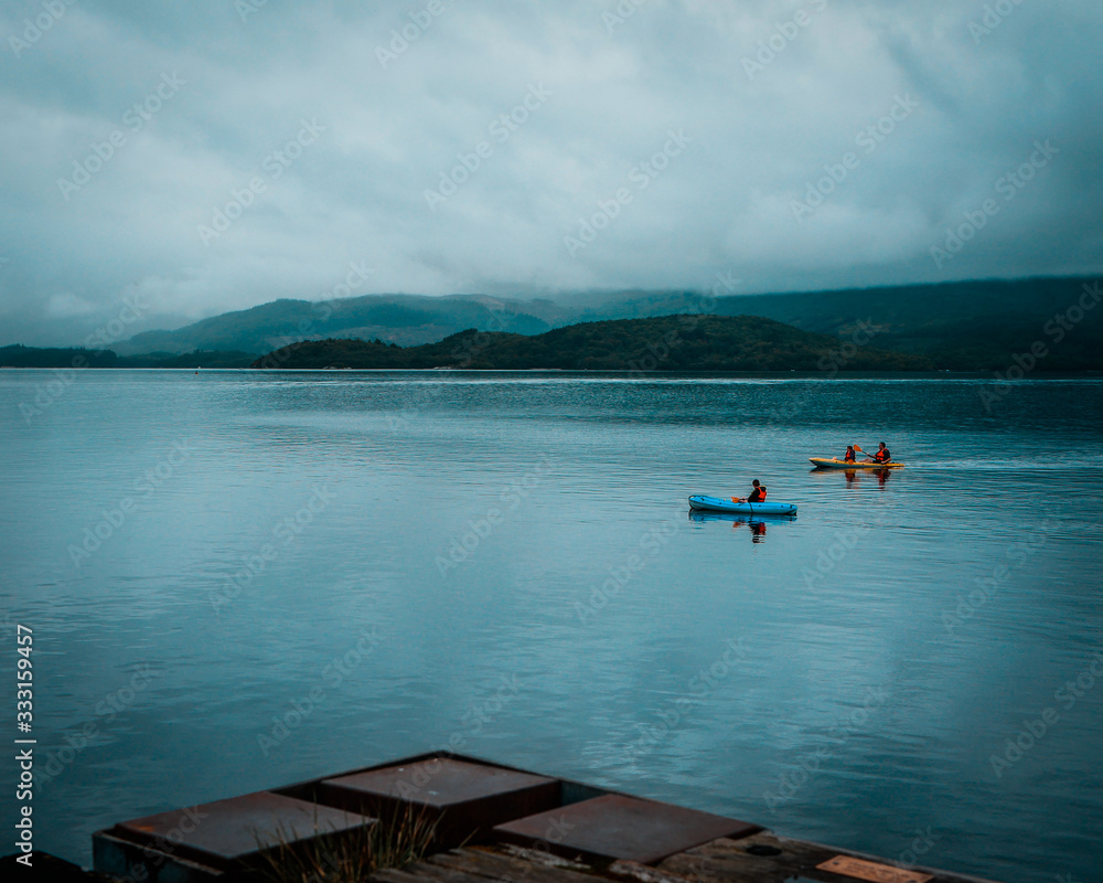 Two Kayaks on a peaceful serene lake in Luss, Scotland. overcast, cloudy day with calm water. Recreational activities. Two Kayaks on a peaceful serene lake in Luss, Scotland. overcast, cloudy day with calm water. Recreational activities.