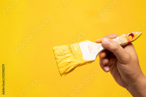 Photography Paint brush, close up hand painter worker painting on surface wall Painting apartment, renovating with yellow color paint