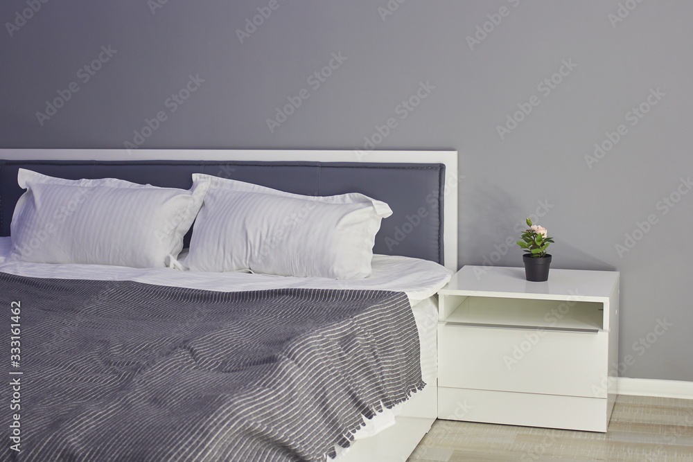 Comfortable bed with pillows in the room, in gray tones