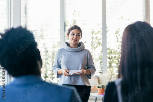 Student presenting project in training room. Young woman in casual holding notebook and speaking before audience. Presentation concept