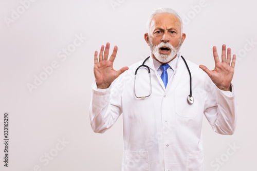 Portrait of  senior doctor in panic on gray background.
