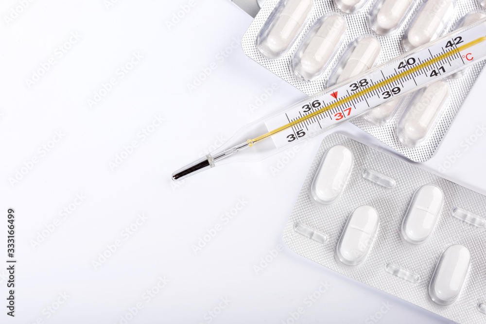 Pills and thermometer on a blue background, the concept of a flu epidemic. Copy space. Pills and thermometer on a blue background, the concept of a flu epidemic. Copy space.