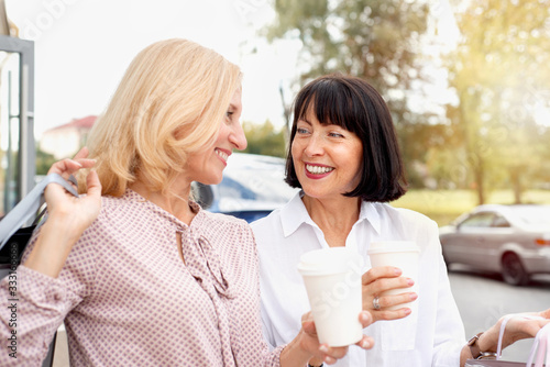 Two mature women having fun while doing shopping and drinking coffee