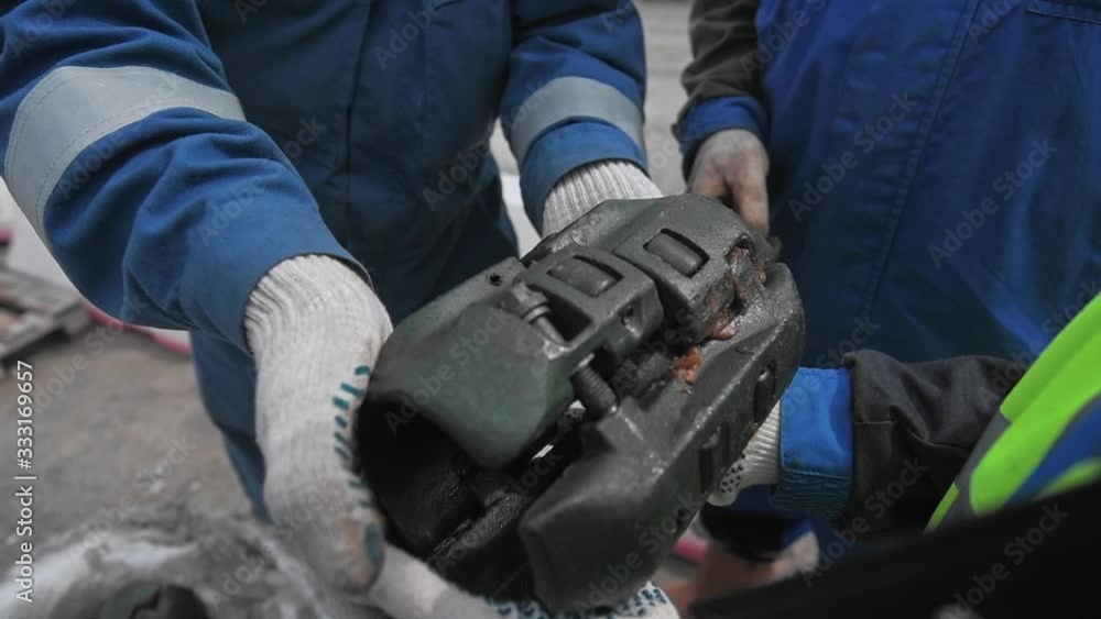 Engineer holds in his hands part of a device for oil production. Spent oil drill detail. Workers in blue overalls. Engineer holds in his hands part of a device for oil production. Spent oil drill detail. Workers in blue overalls.